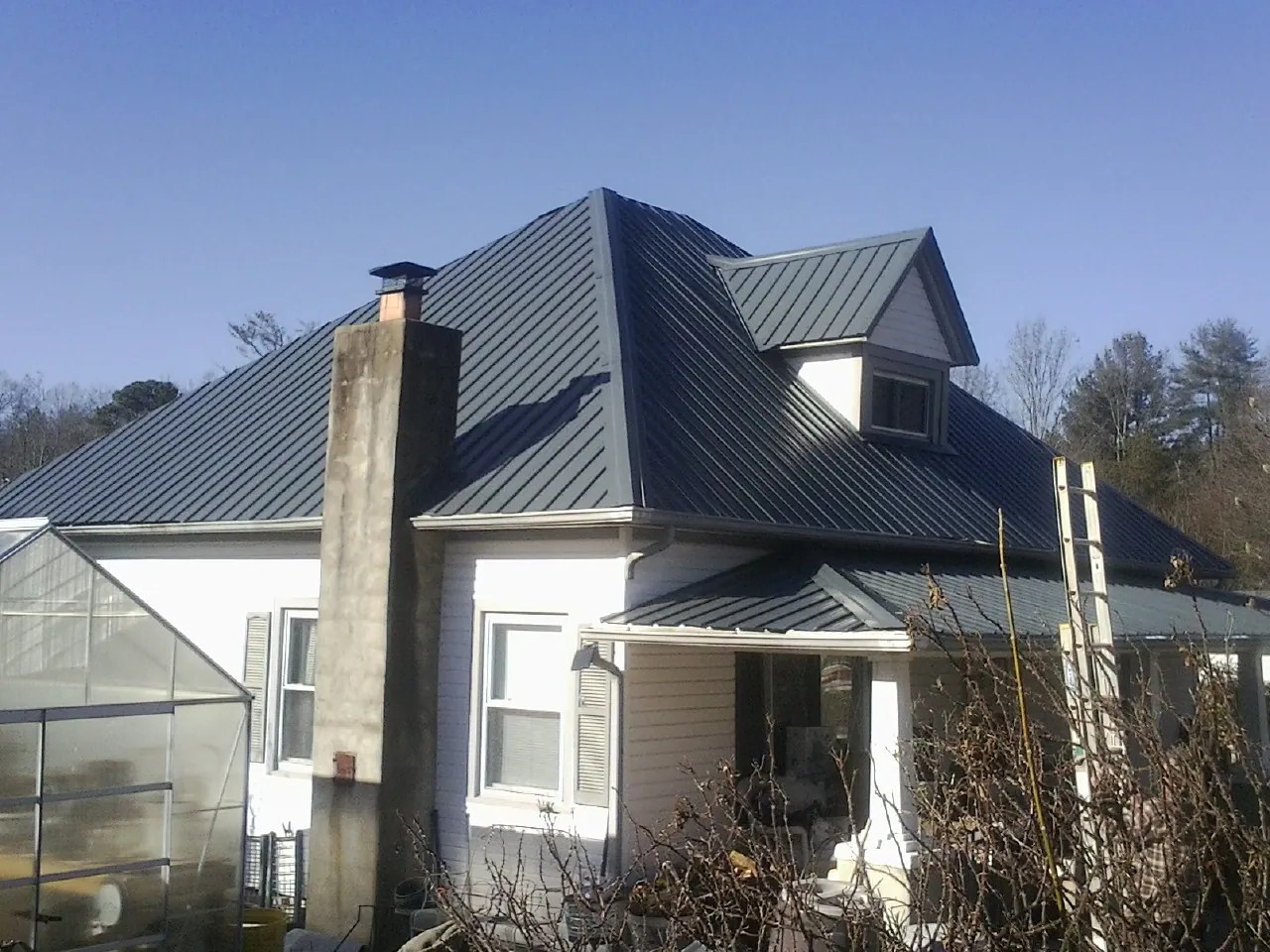 Dark blue standing seam metal roof on a white farmhouse with dormer — Slate & Tile Roof Repair by Roofing Brothers in North Billerica