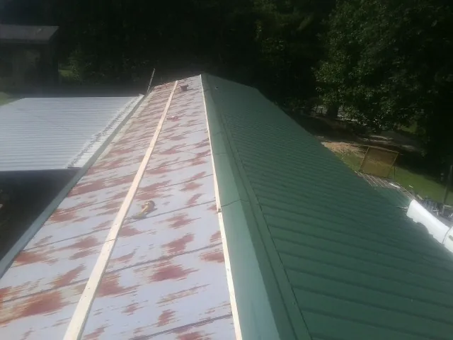 Old rusted panels beside newly installed green metal roofing — Wind Damage Roof Repair by Roofing Brothers in North Billerica