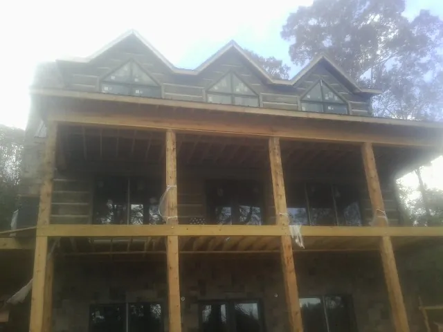 Dormers and porch framing on a large log home under construction — Roof Coating work by our crew in North Billerica