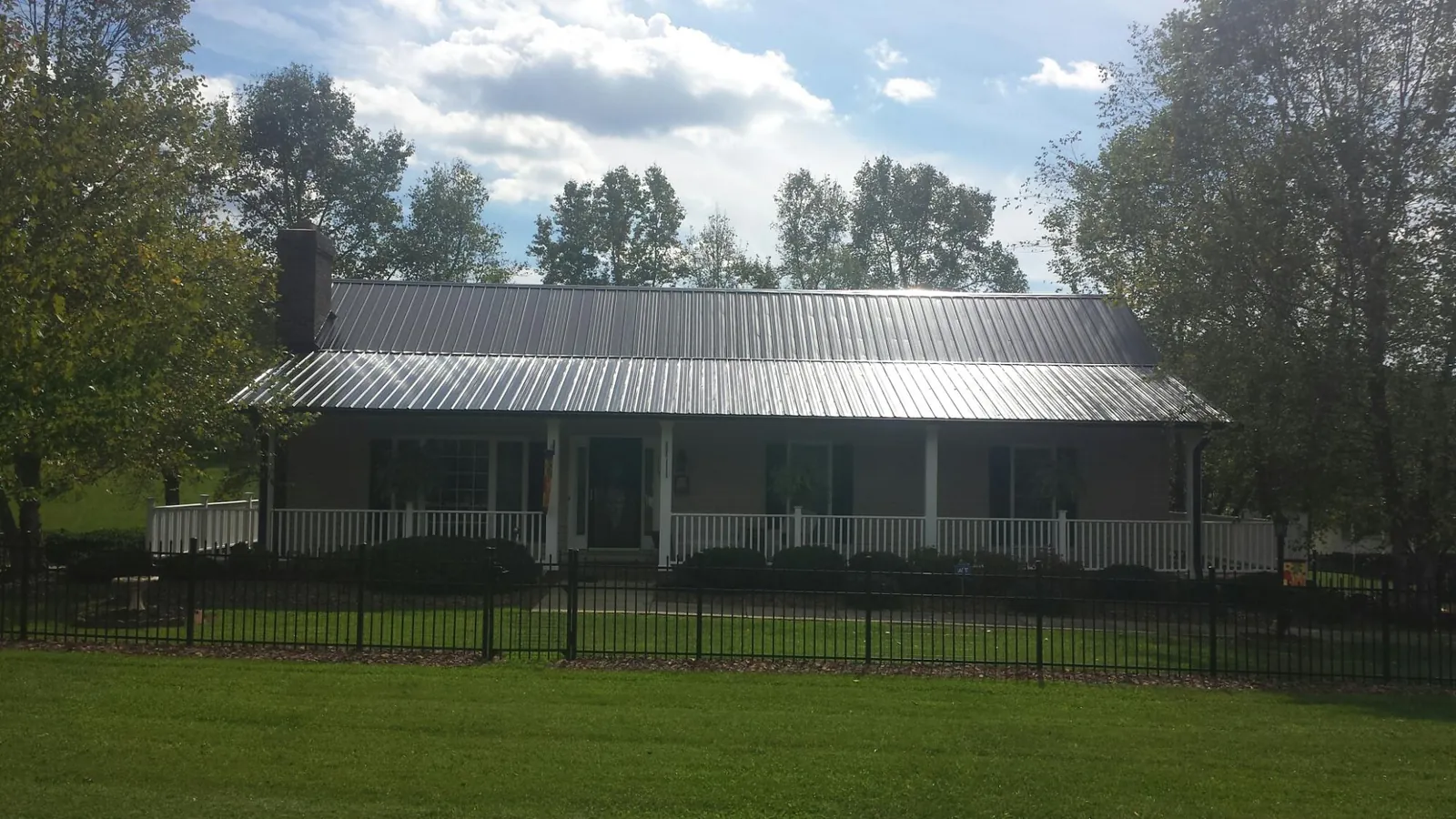 Gray metal roof on a brick ranch with a full width front porch — Gutter Guard Installation work by our crew in North Billerica