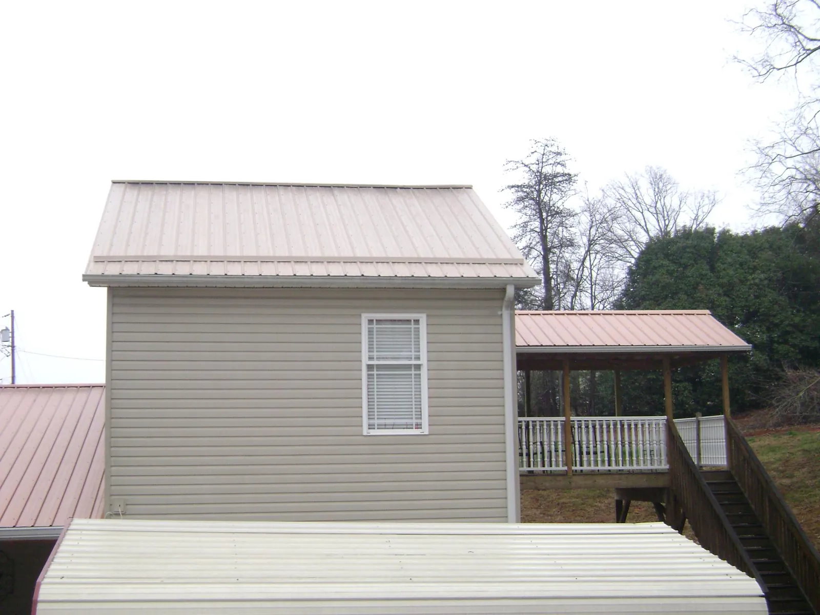 Tan metal roofs on a two story addition and attached porch, from a Roof Replacement job in North Billerica