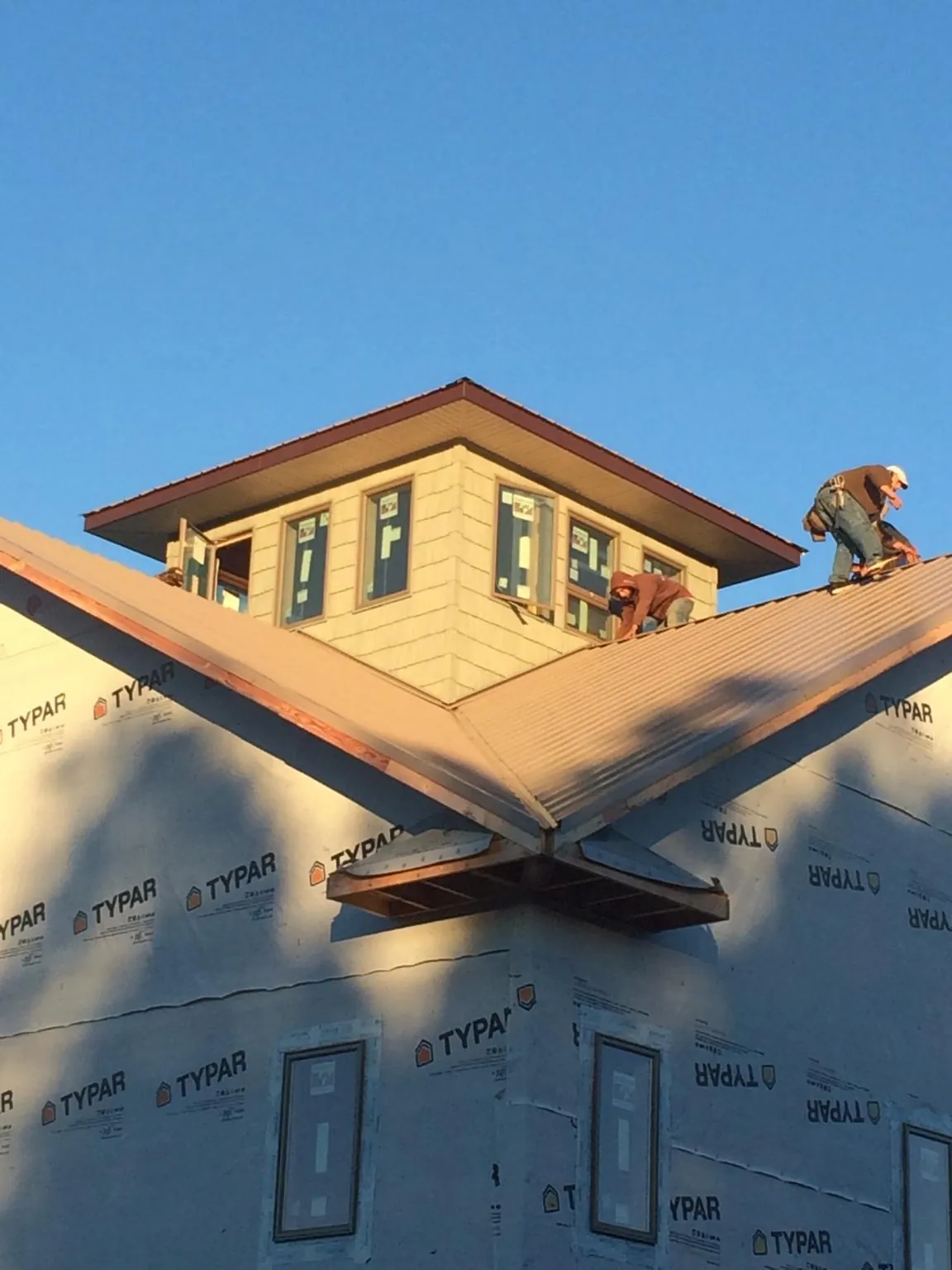 Roofers working around a rooftop cupola on a new metal roof at sunset — Roof Waterproofing in North Billerica by Roofing Brothers